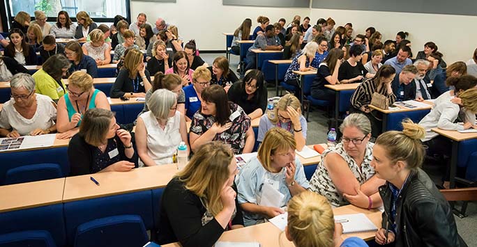 Delegates in discussion during an event in a campus meeting room.