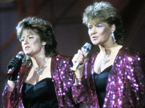 two women in purple sequins singing