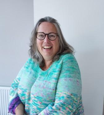 woman in a turquoise jumper smiling facing camera