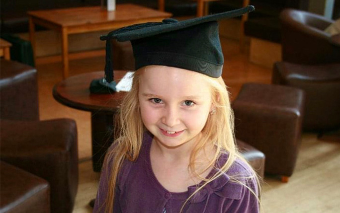 Child pictured in her mother's graduation cap