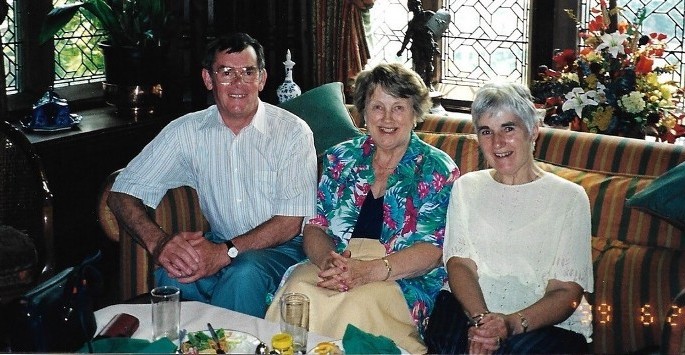 Man and two women sitting on sofa facing camera