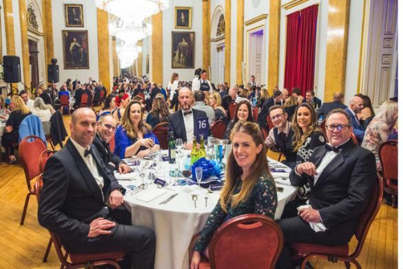 Alumni sitting at a round table posing for a photo in the Liverpool Town Hall