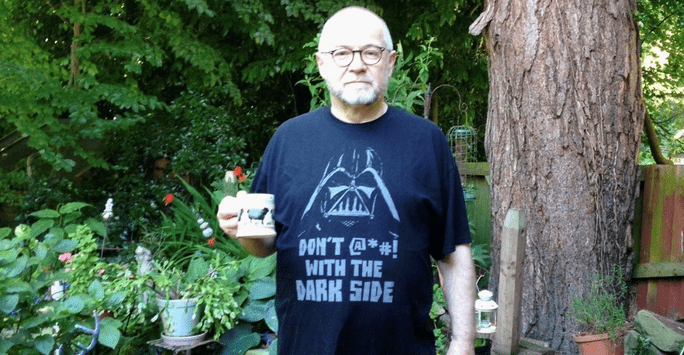 Shaun Jackson in his garden, holding a cup of tea