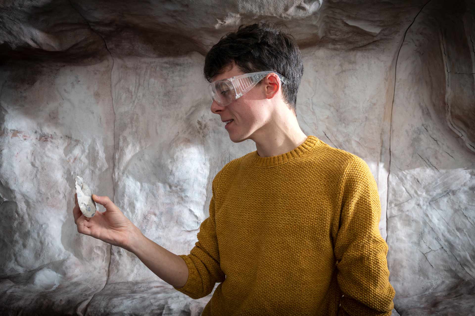 Student in flint knapping suite looking at fragment of object