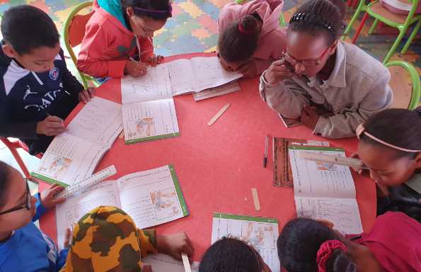 Children gathered round a table drawing local heritage they feel attached to and writing.