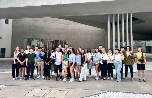 Group of people standing in front of a brutalist building.