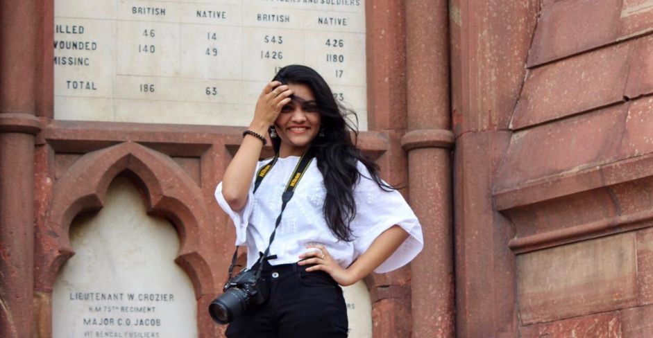 Graduate in front of a building inc campus