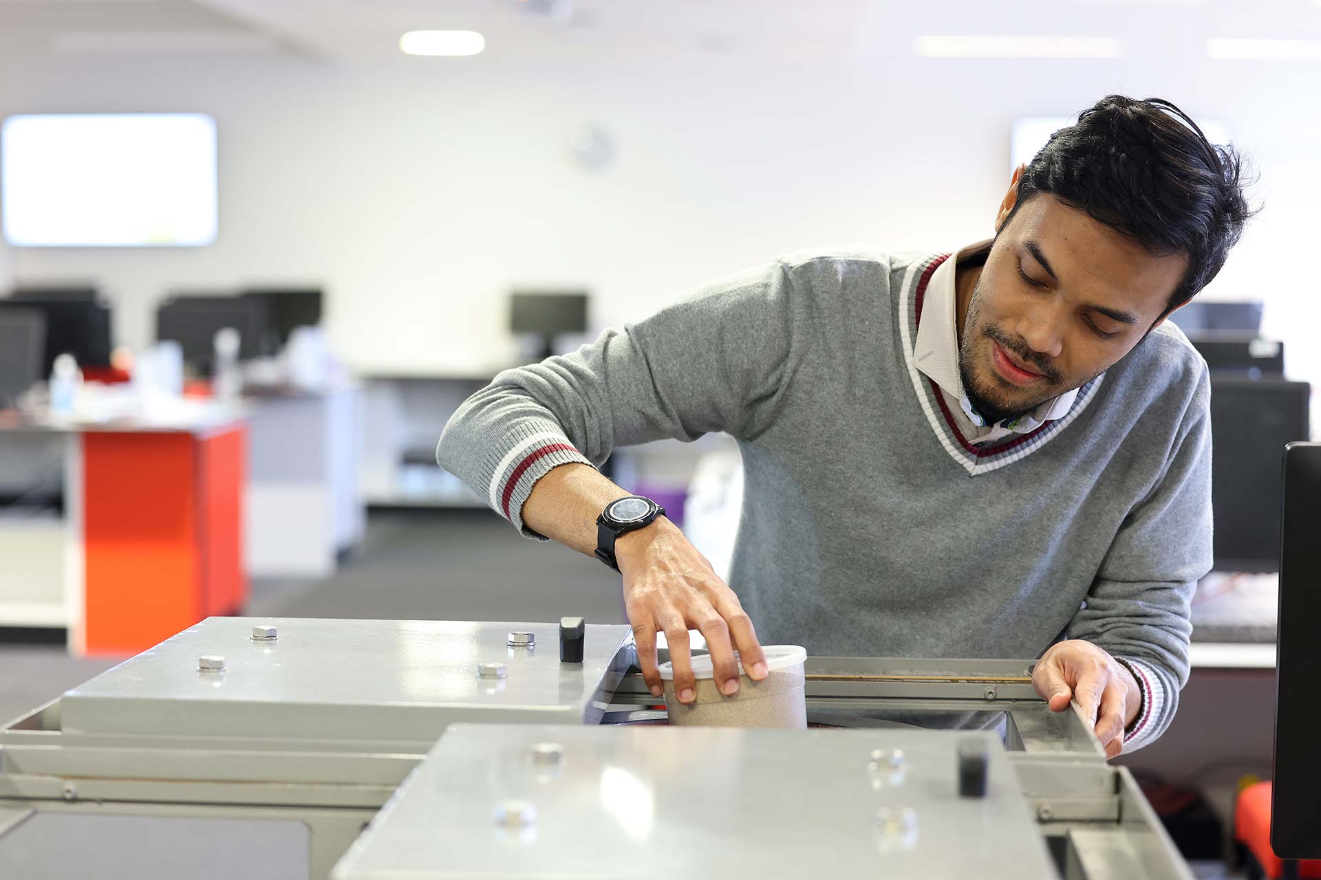 A student prepares to work in a laboratory, taking a container out of a cupboard.