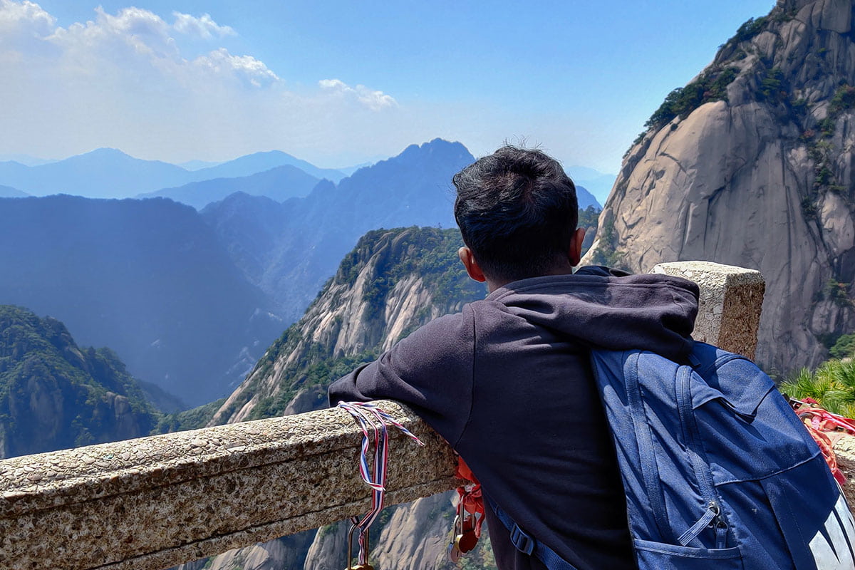 Image of the back of a male student's head. He looks out at a mountain vista.