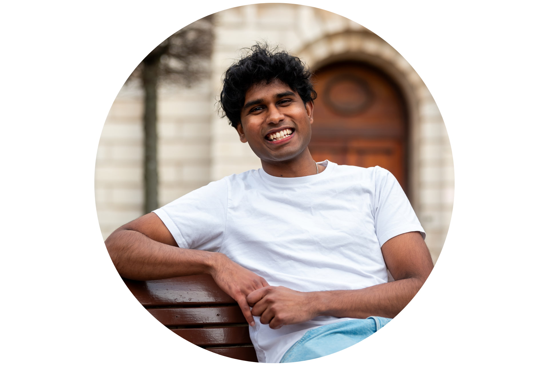 A student smiling on a bench.