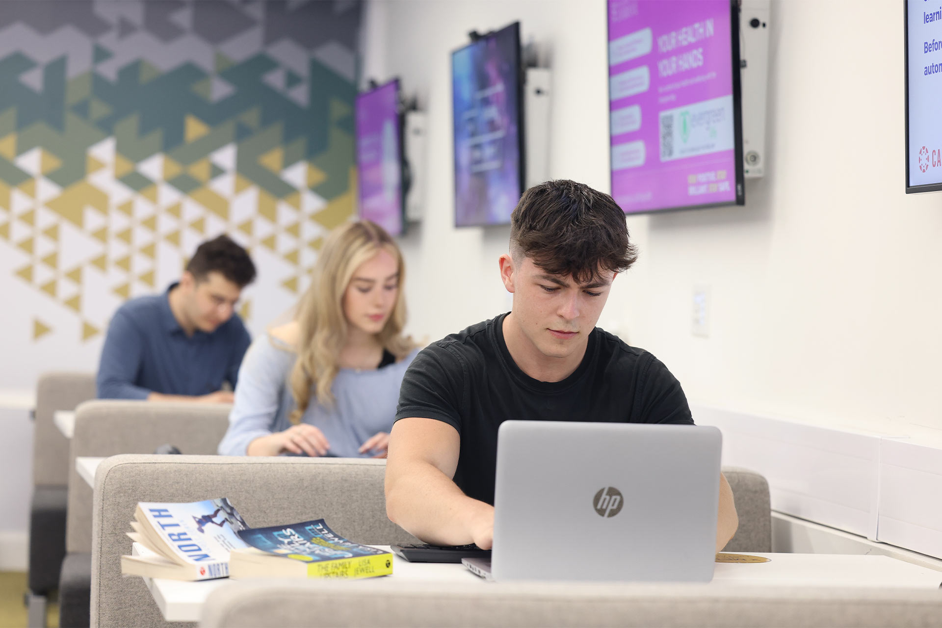 Students on campus sitting at tables using laptops