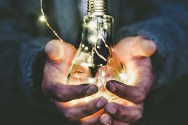 Dirty hands holding an illuminated lightbulb