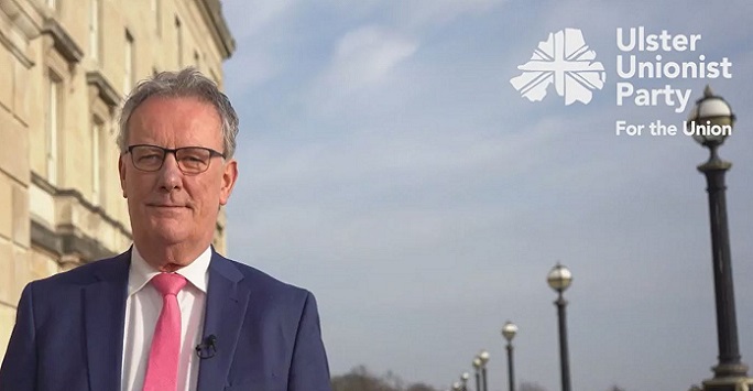 mike nesbitt standing outside sandstone building