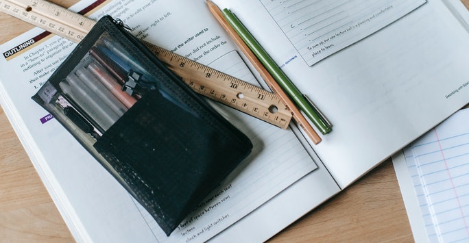 pens and ruler on top of a textbook