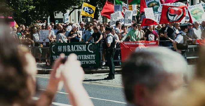 policeman at a protest, out of focus photo being taken in the foreground