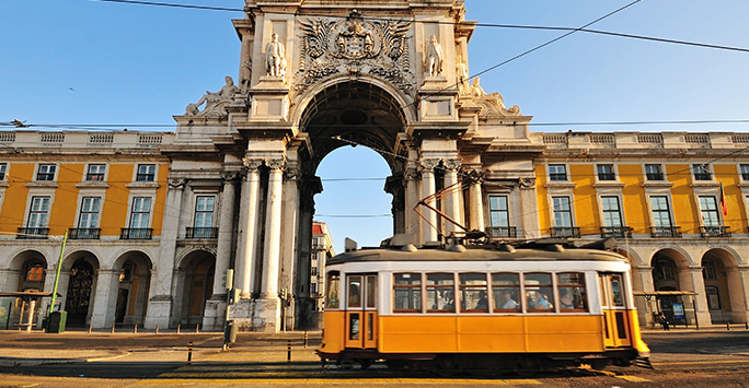 A bright yellow and white travels along a street in Lisbon