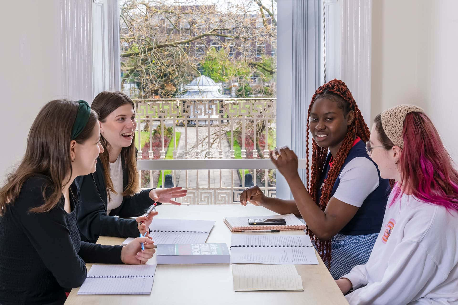 students sat on a table smiling and communicating with each other