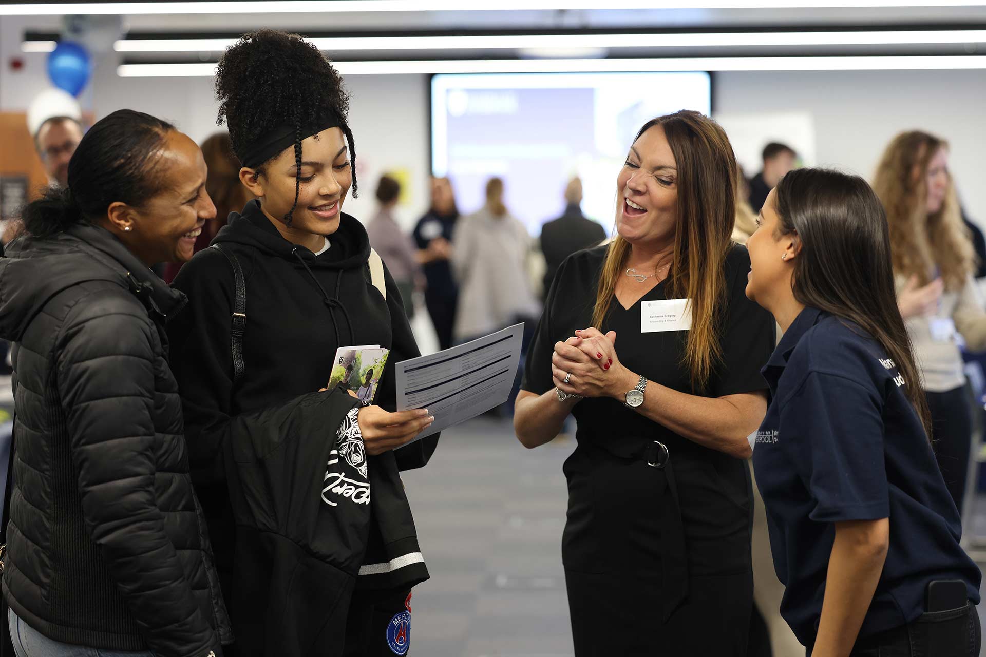 A member of staff speaks to a prospective student and guest at an open day.