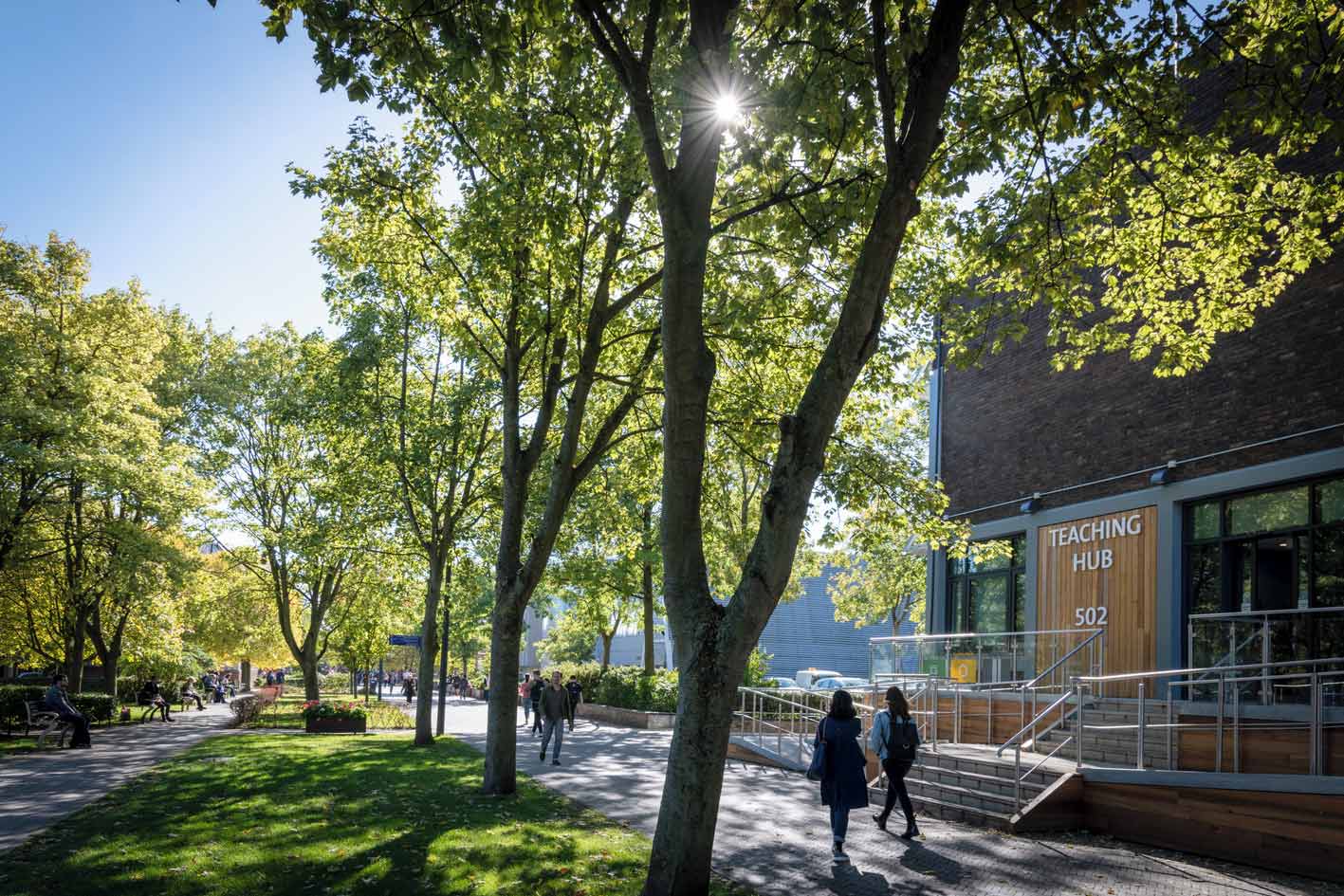 Students walking past the 502 Teaching Hub on the University of Liverpool campus on a sunny day