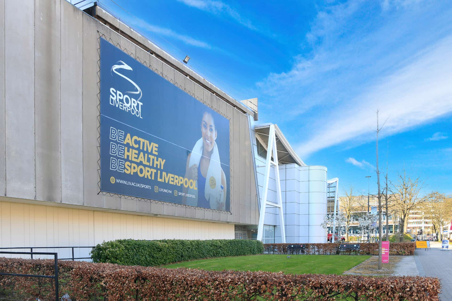 The front of the Sport Centre on campus with a billboard on the front that says, 