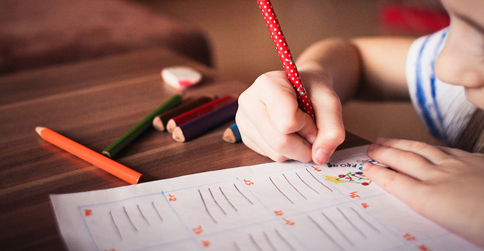 Child writing with crayons