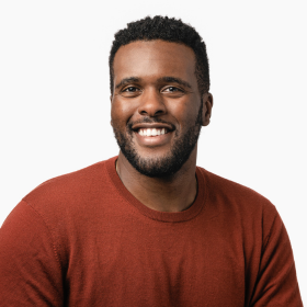 A headshot of a man with an orange top smiling