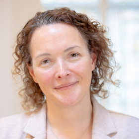 A headshot of a woman with curly hair