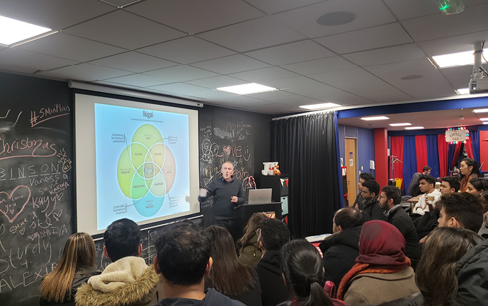 Man talking and presenting to a room filled with people