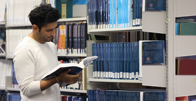 PhD students reading a book in the library