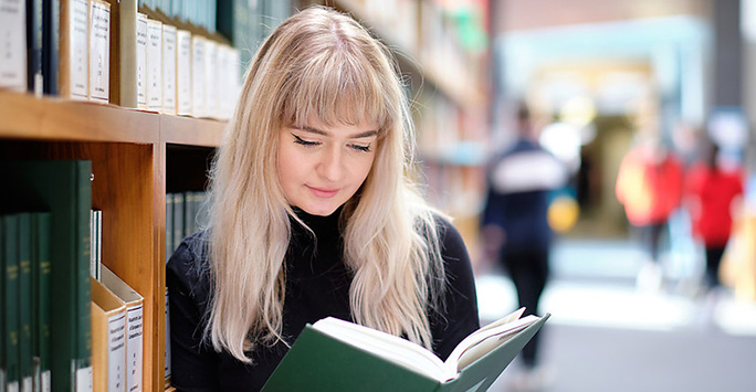 Postgraduate student reading book in library