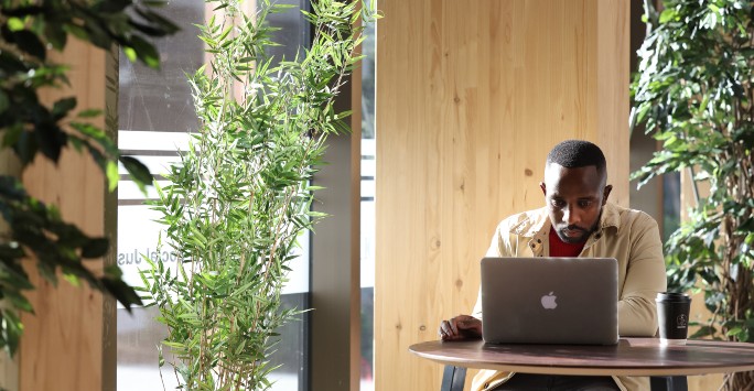 A student sitting at a table working on a laptop