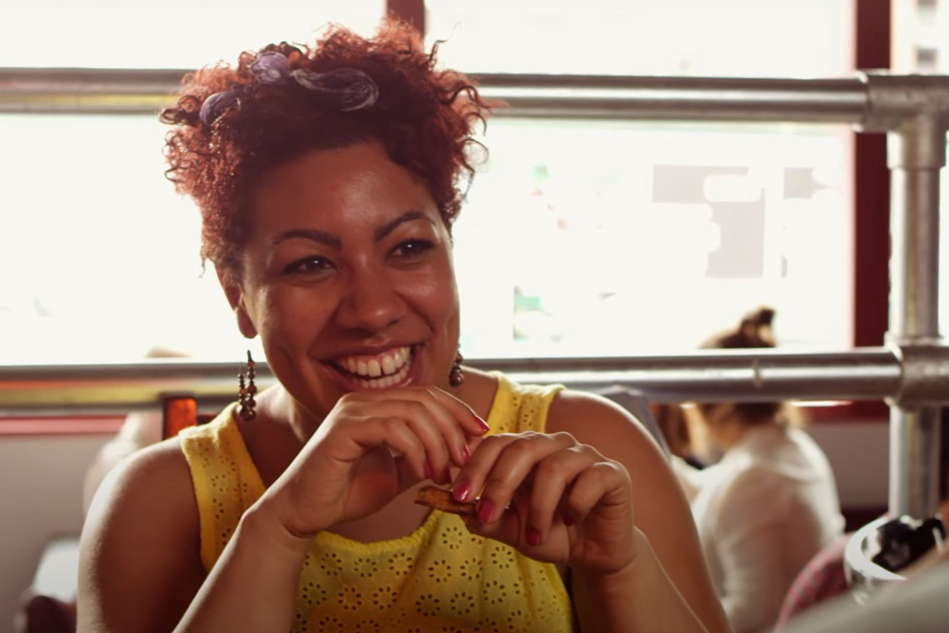 Woman in bright yellow top smiling at camera in a cafe